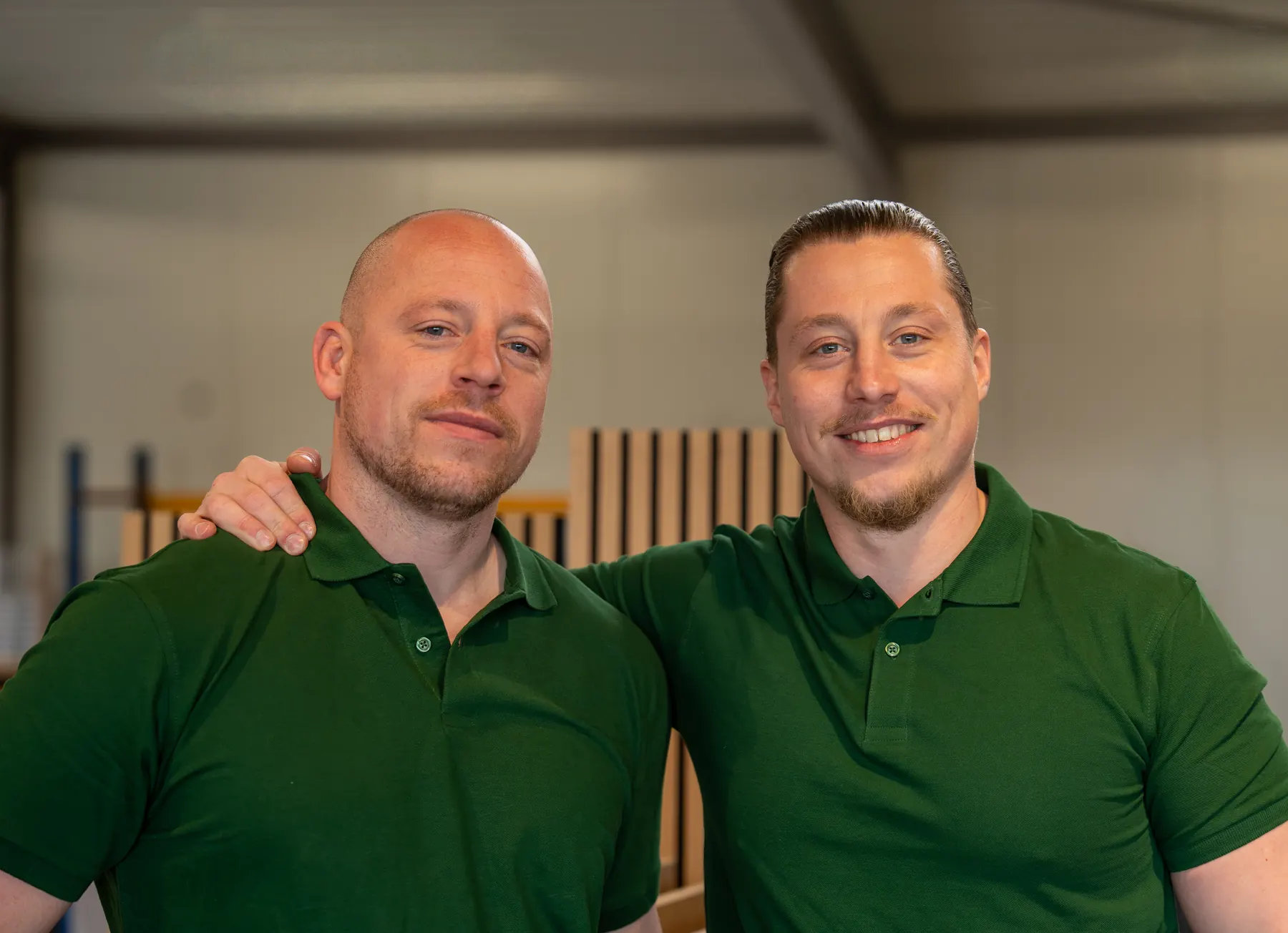 Stevie, eigenaar van VerhuisMeesters, en Nick, aanspreekpunt aan de telefoon, in groene polo’s in een lichte bedrijfshal