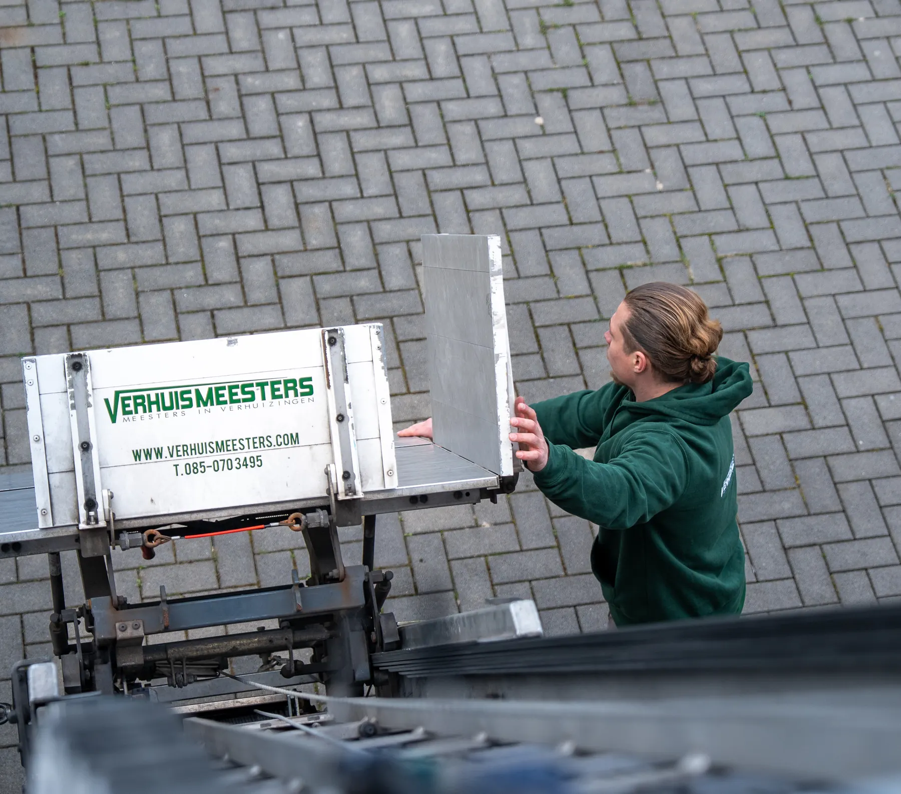 Van bovenaf: een verhuizer van VerhuisMeesters zet het plateau van de eigen verhuislift klaar